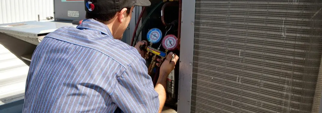 HVAC technician servicing a condenser unit in Sheridan